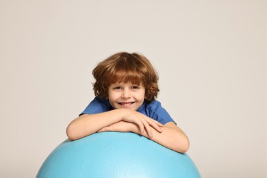 Little boy with fitness ball on light grey background