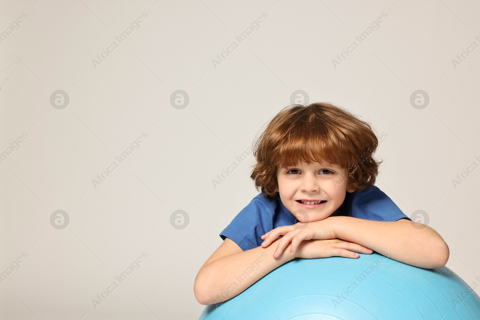 Photo of Little boy with fitness ball on light grey background, space for text