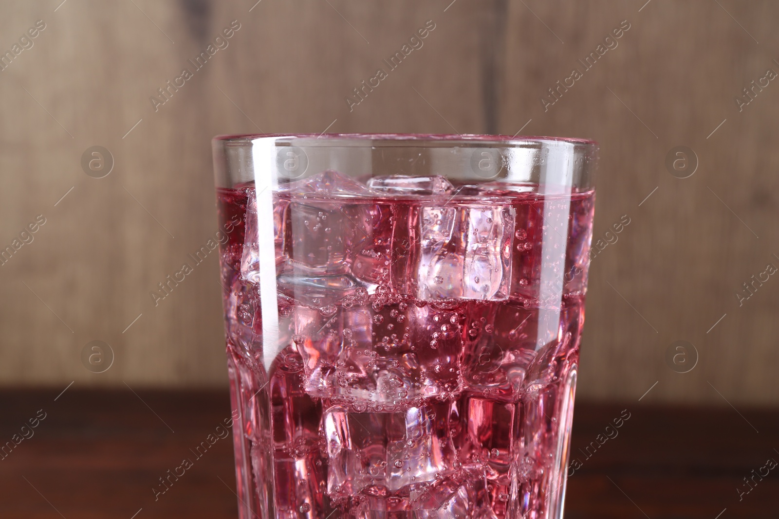 Photo of Sweet soda water with ice cubes in glass on blurred background, closeup