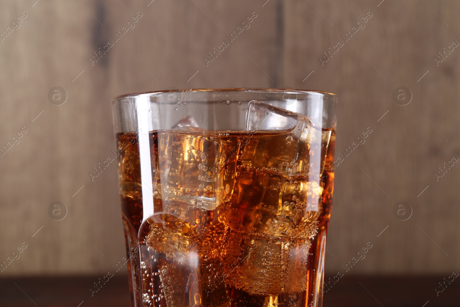 Photo of Sweet soda water with ice cubes in glass on blurred background, closeup