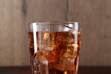 Photo of Sweet soda water with ice cubes in glass on blurred background, closeup