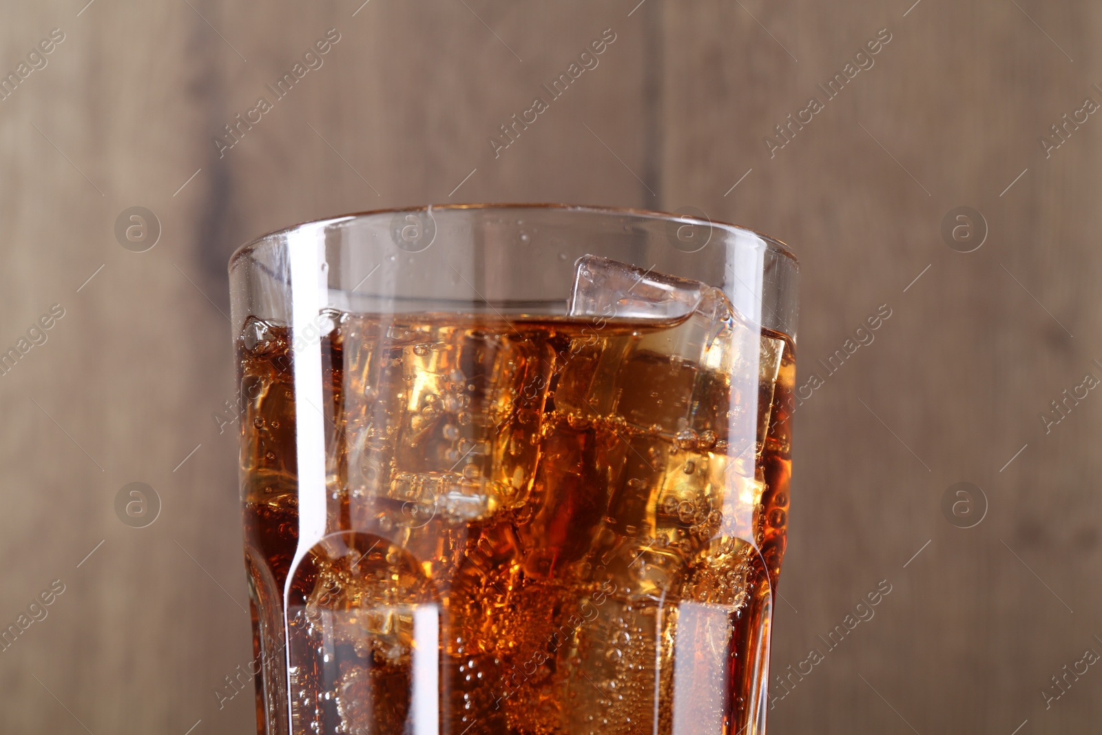 Photo of Sweet soda water with ice cubes in glass on blurred background, closeup