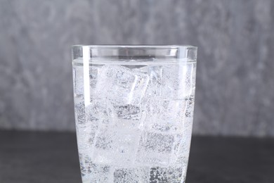 Photo of Refreshing soda water with ice cubes in glass on blurred background, closeup