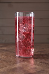 Photo of Sweet soda water with ice cubes in glass on wooden table