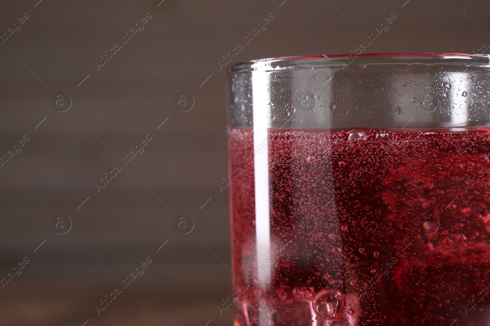 Photo of Sweet soda water with ice cubes in glass on blurred background, closeup. Space for text