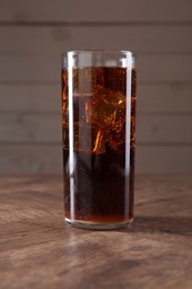 Photo of Sweet soda water with ice cubes in glass on wooden table, closeup