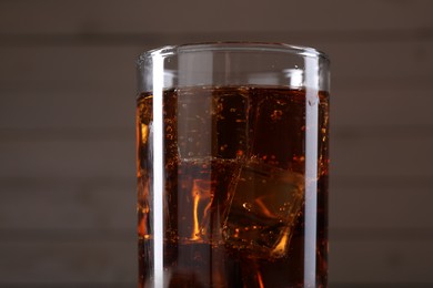 Photo of Sweet soda water with ice cubes in glass on blurred background, closeup