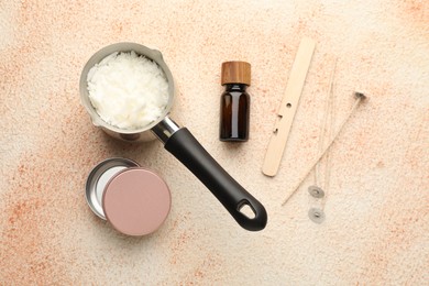 Photo of Making handmade candles. Soy wax, essential oil and wicks on beige textured table, flat lay