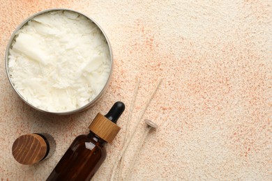 Photo of Making handmade candles. Soy wax in jar, essential oils and wicks on beige textured table, flat lay. Space for text