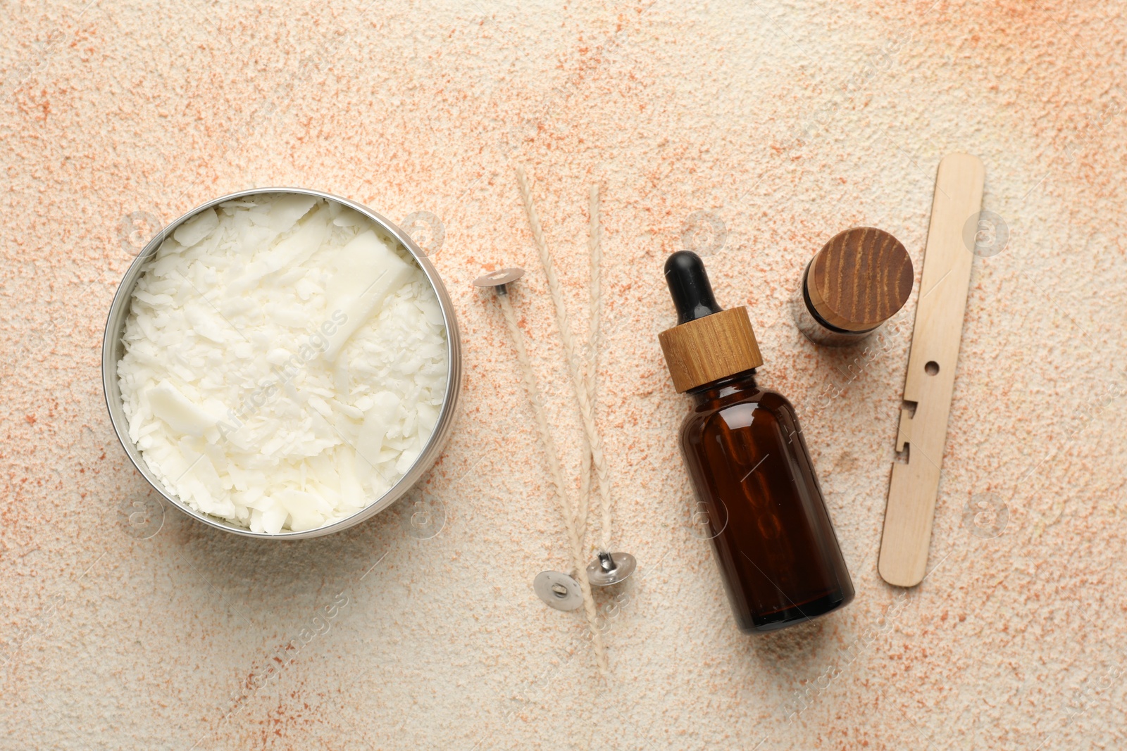 Photo of Making handmade candles. Soy wax in jar, essential oils and wicks on beige textured table, flat lay