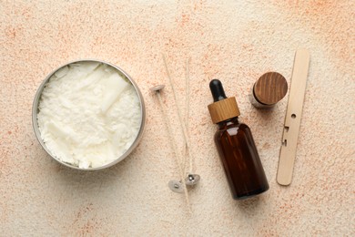 Making handmade candles. Soy wax in jar, essential oils and wicks on beige textured table, flat lay