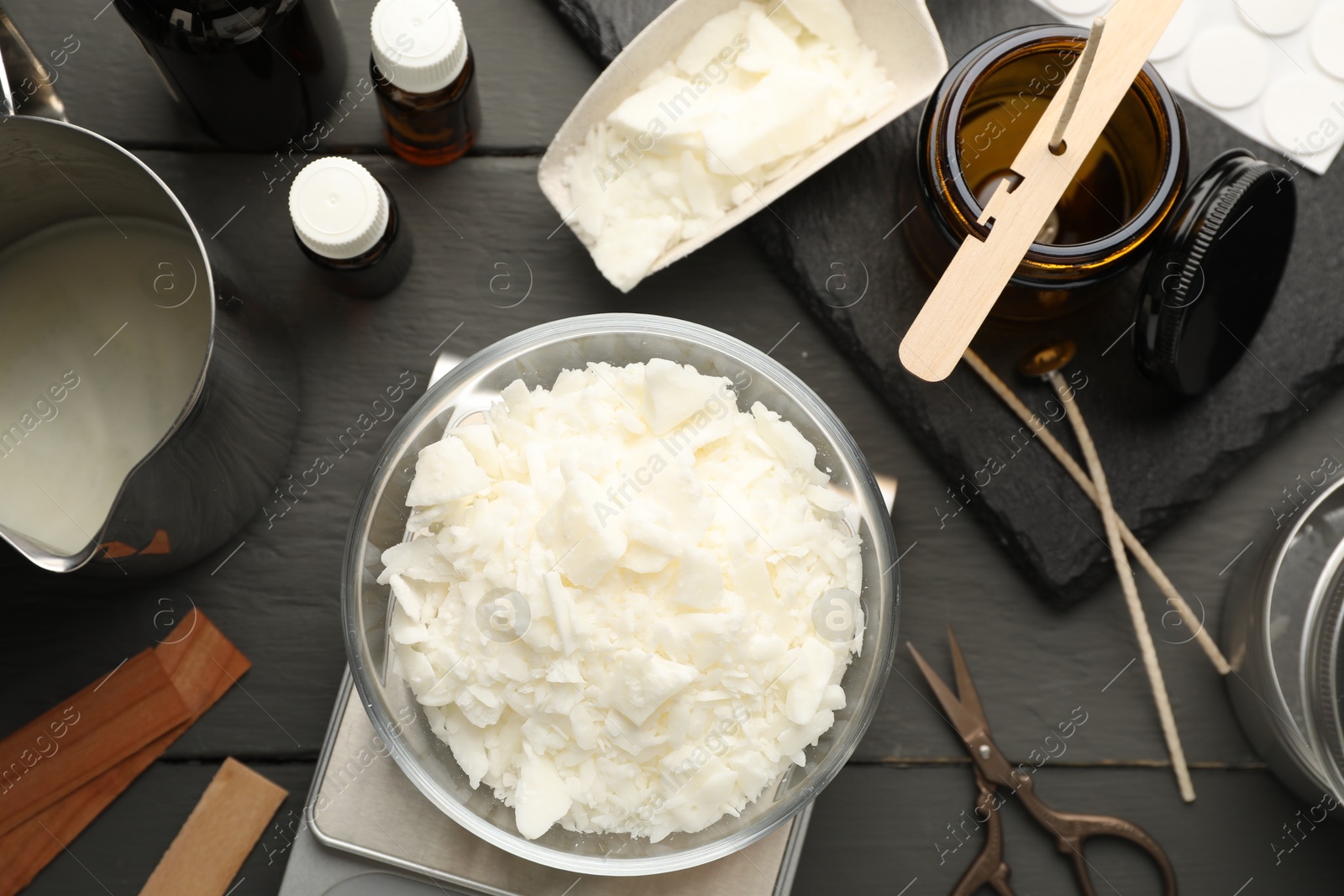 Photo of Soy wax, essential oils and different tools for making candles on grey wooden table, flat lay