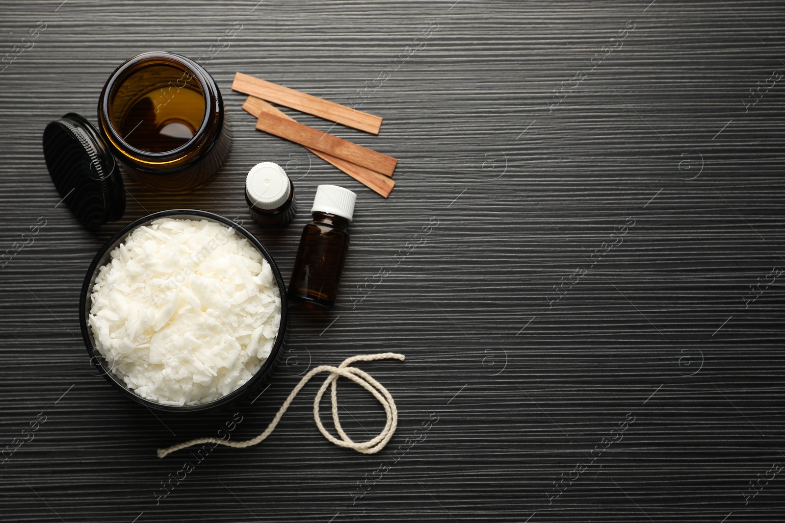 Photo of Making handmade candles. Soy wax, essential oils, twine, wooden wicks and jar on black textured table, flat lay. Space for text