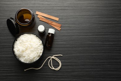 Making handmade candles. Soy wax, essential oils, twine, wooden wicks and jar on black textured table, flat lay. Space for text