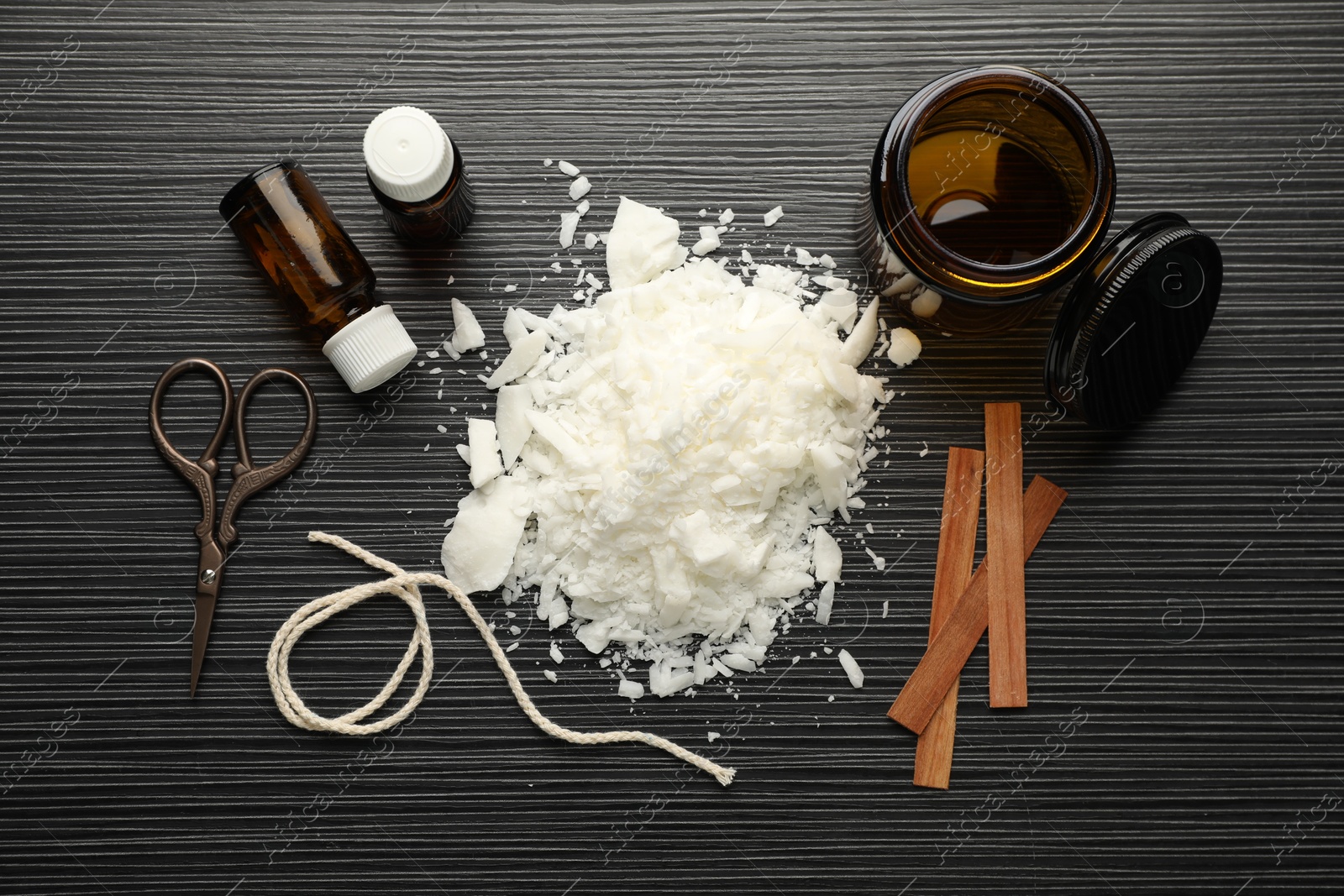 Photo of Making handmade candles. Soy wax, essential oils, twine, wooden wicks and jar on black textured table, flat lay