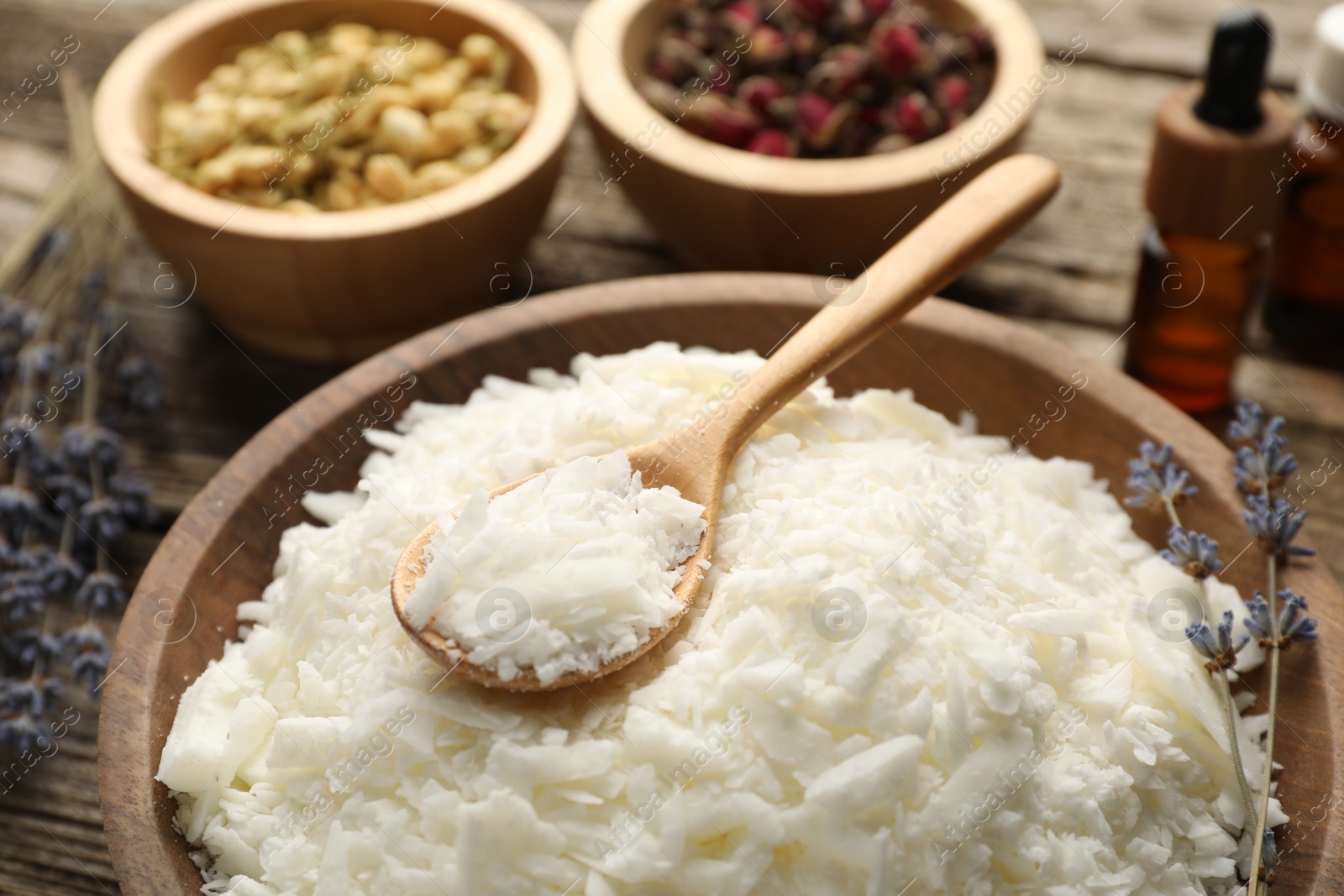 Photo of Soy wax in bowl and other different ingredients for making candles on table, closeup