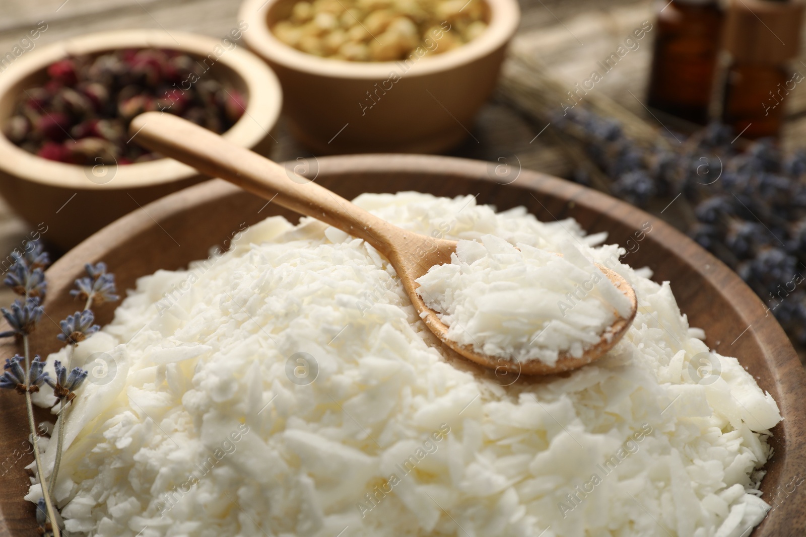 Photo of Soy wax in bowl and other different ingredients for making candles on table, closeup