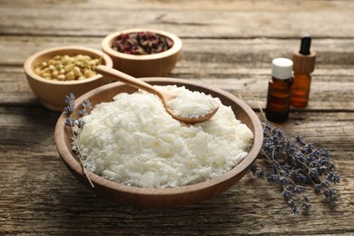 Soy wax in bowl and other different ingredients for making candles on wooden table, closeup