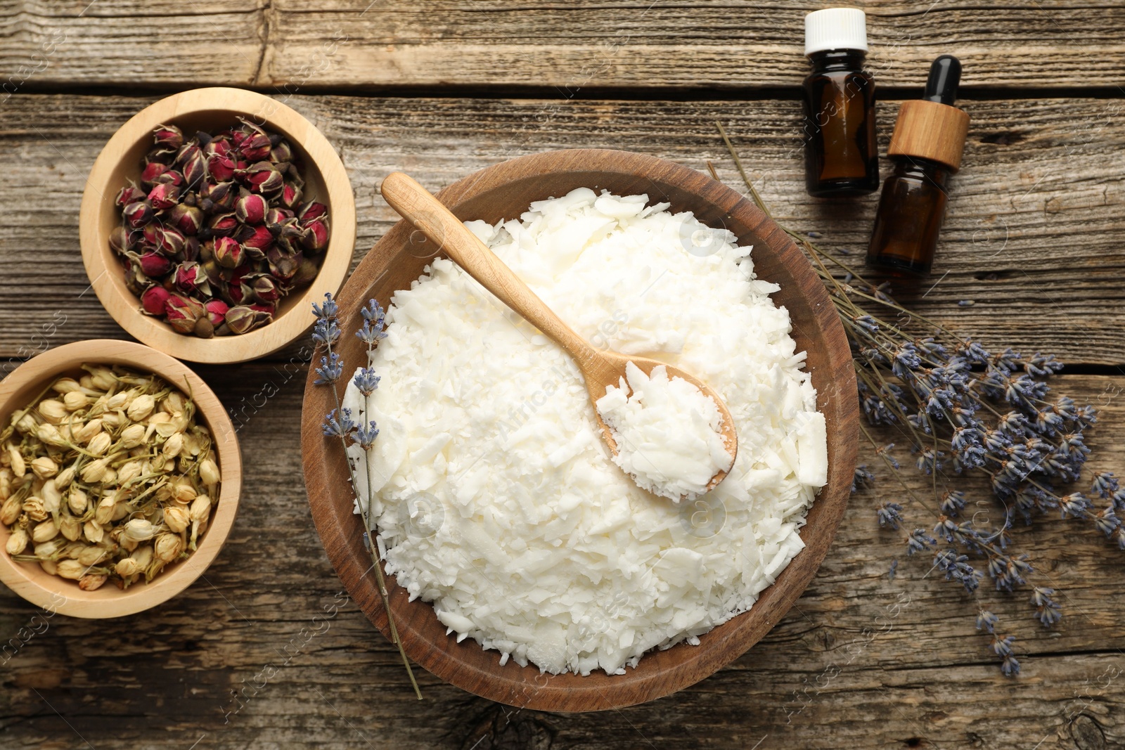 Photo of Soy wax in bowl and other different ingredients for making candles on wooden table, flat lay