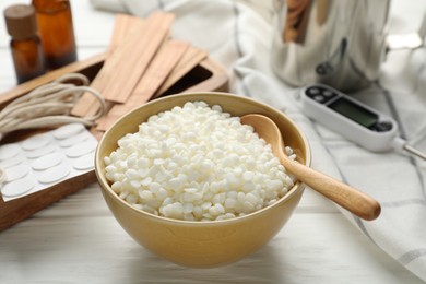 Soy wax in bowl and different tools for making candles on white wooden table, closeup