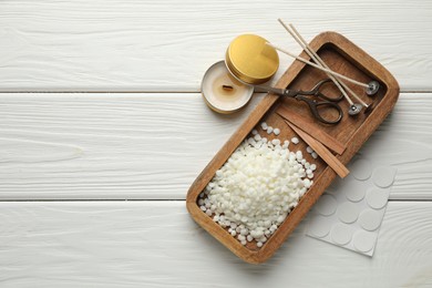 Photo of Soy wax, wicks, sticker, scissors and candle on white wooden table, flat lay. Space for text