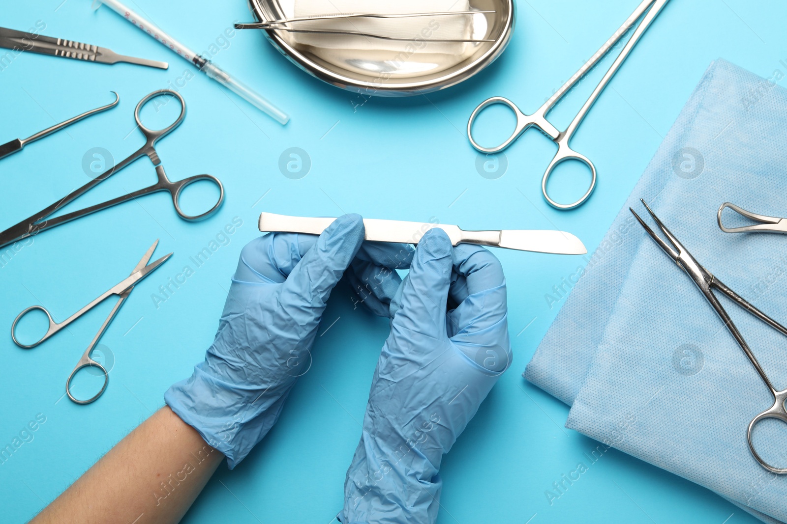 Photo of Doctor with different surgical tools on light blue background, top view