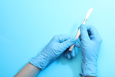 Photo of Doctor with surgical scalpel on light blue background, top view. Space for text