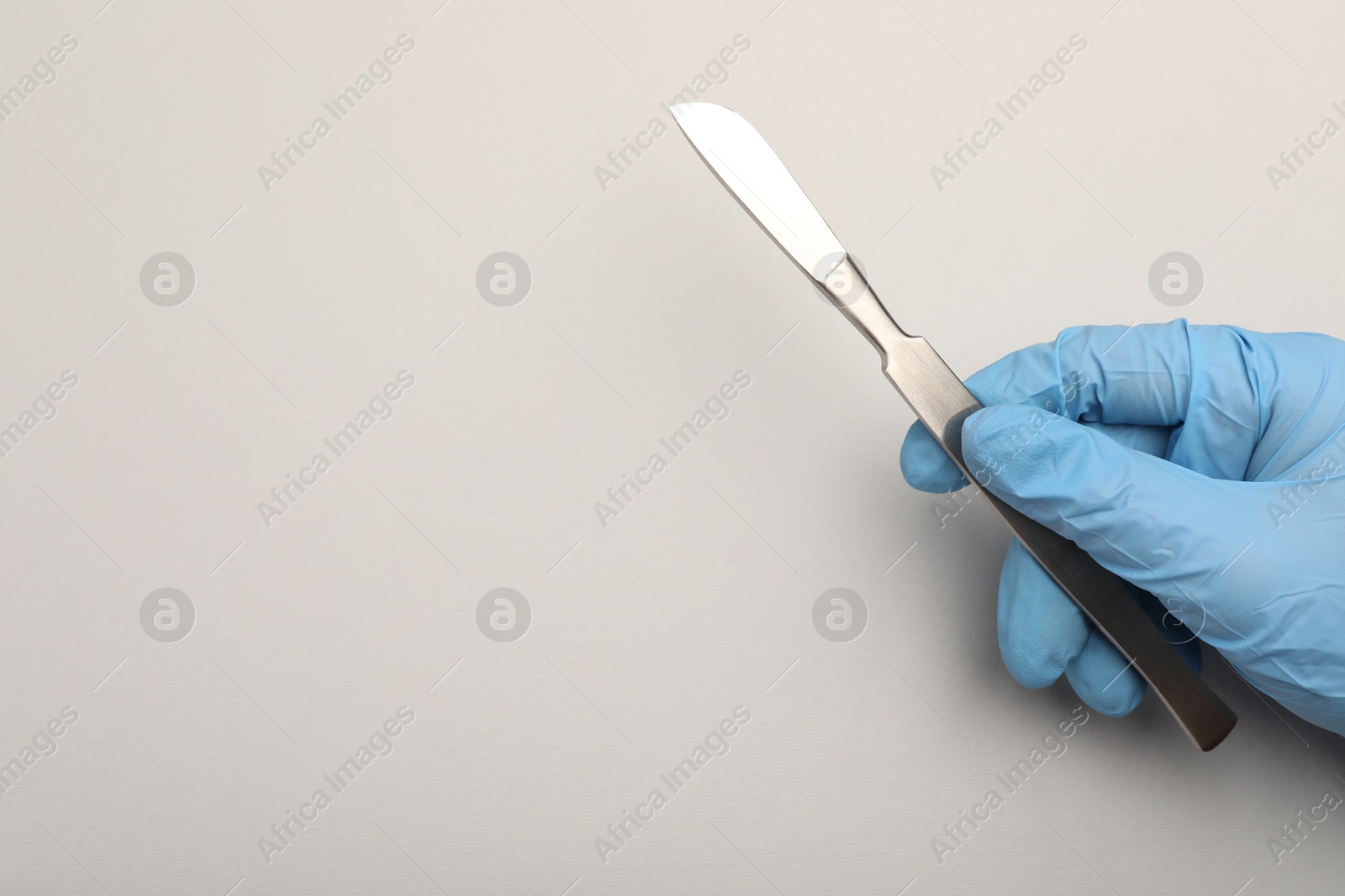 Photo of Doctor with surgical scalpel on light background, top view. Space for text