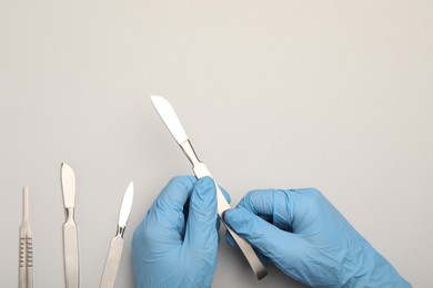 Photo of Doctor with surgical scalpels on light background, top view. Space for text