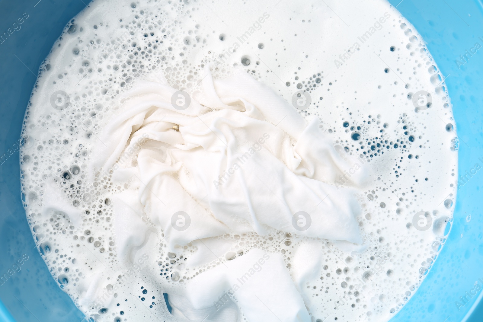 Photo of White clothes soaked in water before washing, top view