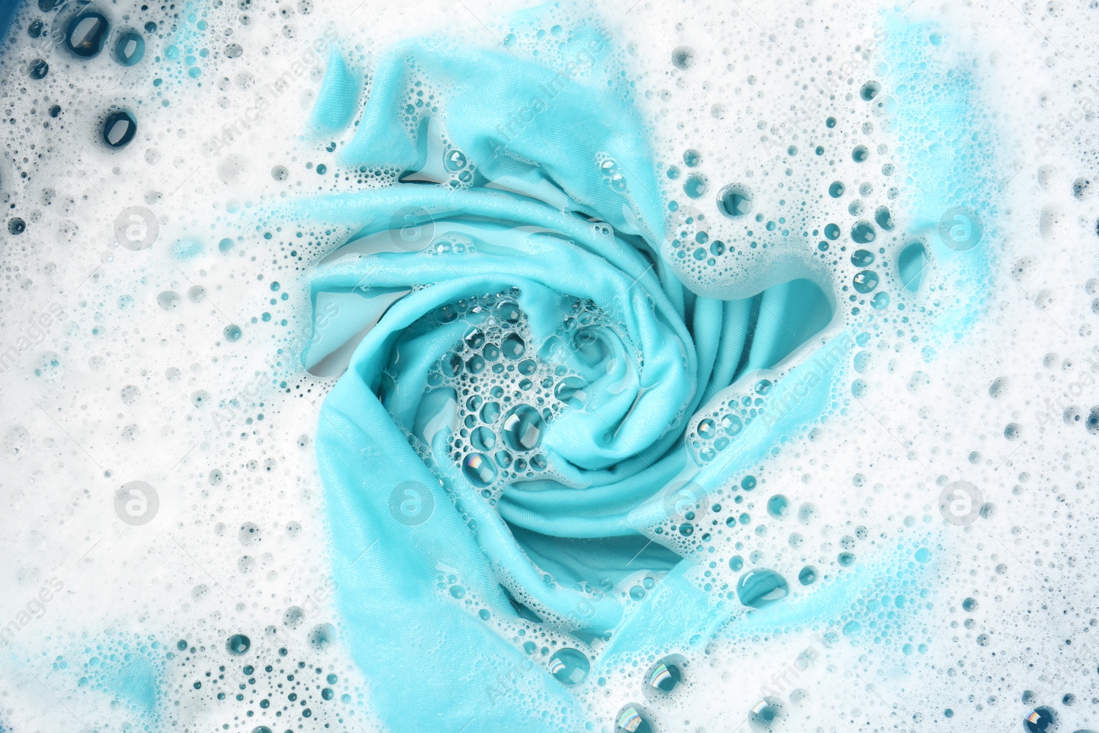 Photo of Turquoise clothes soaked in water before washing, top view