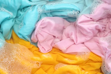 Photo of Colorful clothes soaked in water before washing, top view