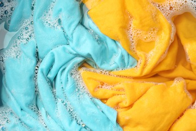 Photo of Colorful clothes soaked in water before washing, top view