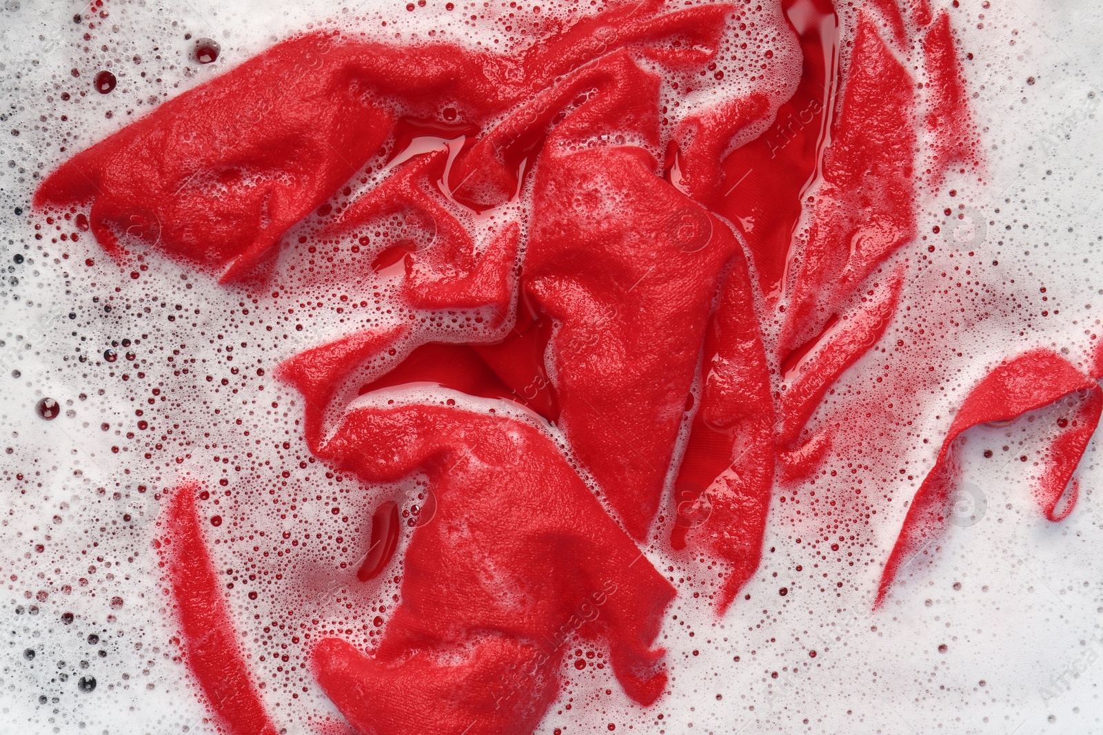 Photo of Red clothes soaked in water before washing, top view