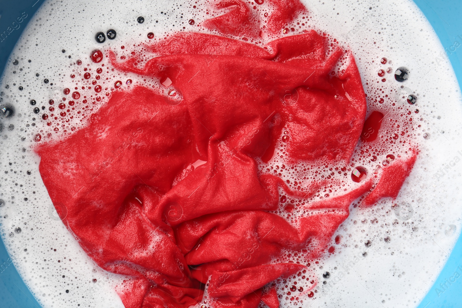 Photo of Red clothes soaked in water before washing, top view