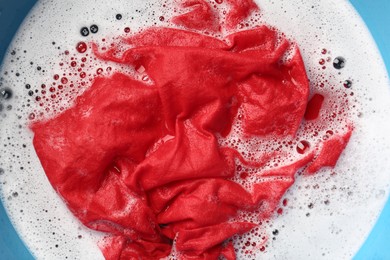 Photo of Red clothes soaked in water before washing, top view