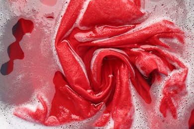 Photo of Red clothes soaked in water before washing, top view