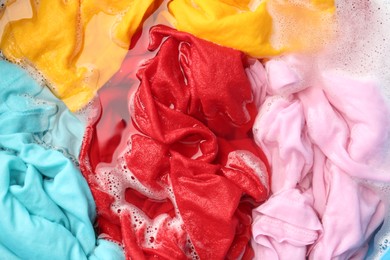 Photo of Colorful clothes soaked in water before washing, top view