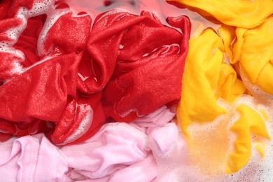 Photo of Colorful clothes soaked in water before washing, top view