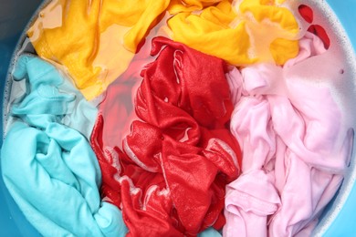 Photo of Colorful clothes soaked in water before washing, top view