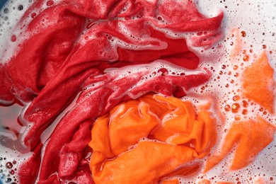 Photo of Colorful clothes soaked in water before washing, top view