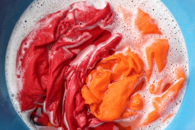 Photo of Colorful clothes soaked in water before washing, top view