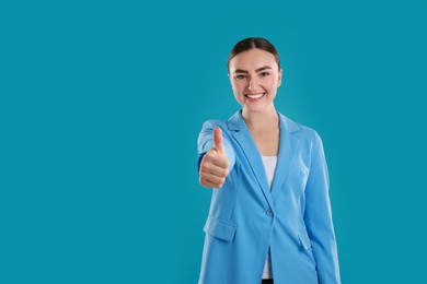 Photo of Happy woman showing thumbs up on light blue background, space for text. Like gesture