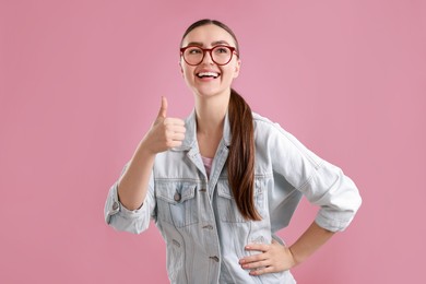 Happy woman showing thumbs up on pink background. Like gesture