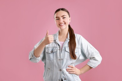 Happy woman showing thumbs up on pink background. Like gesture