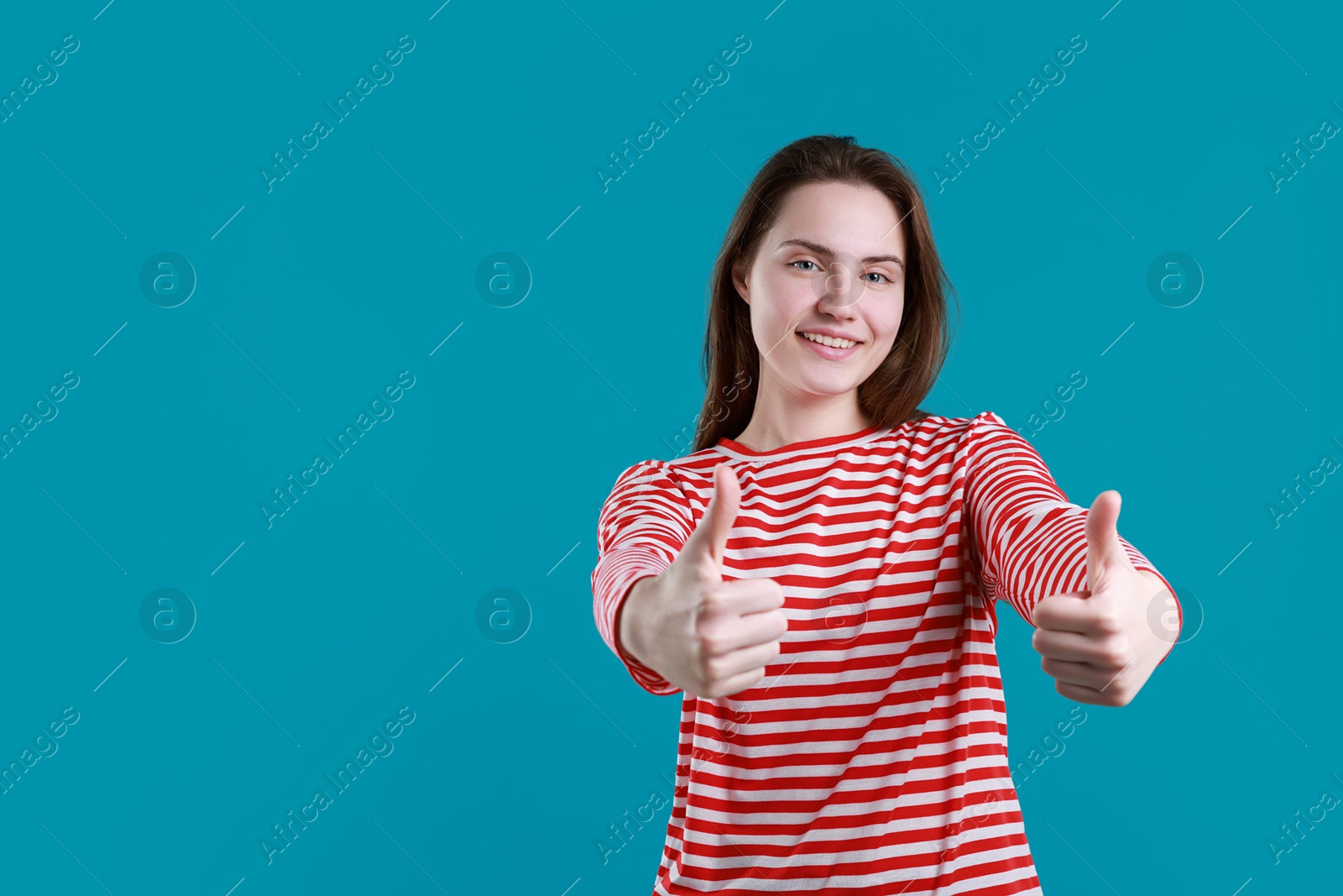 Photo of Happy woman showing thumbs up on light blue background, space for text. Like gesture