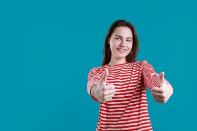 Photo of Happy woman showing thumbs up on light blue background, space for text. Like gesture