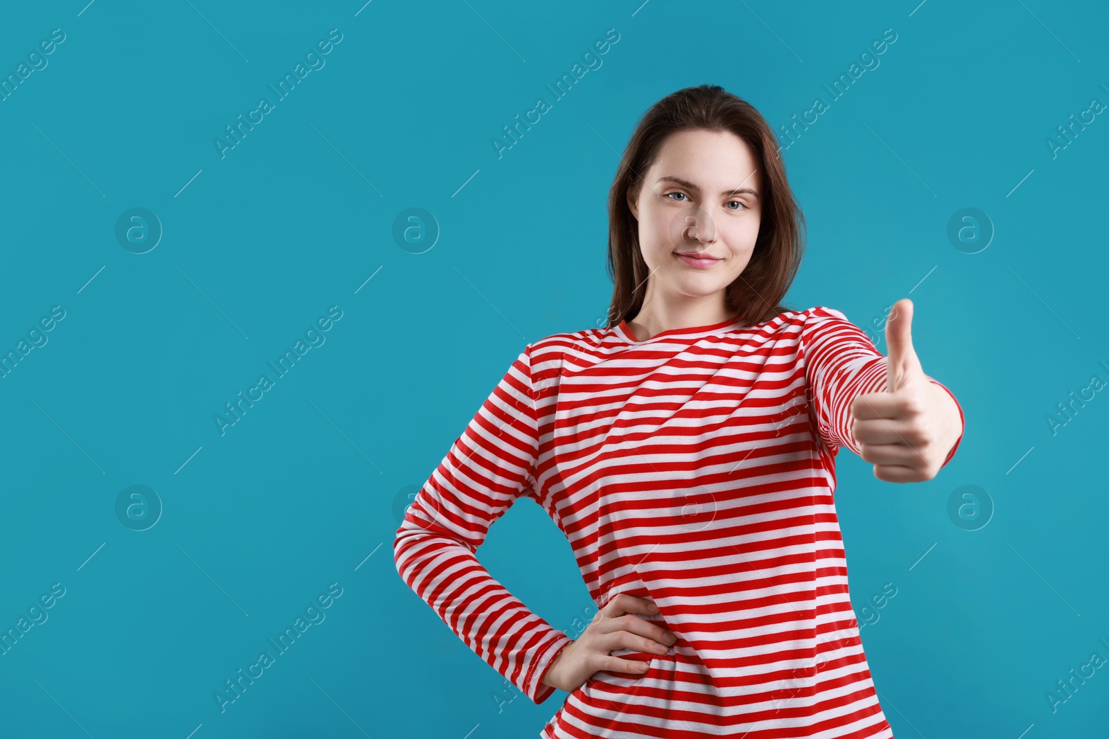 Photo of Woman showing thumbs up on light blue background, space for text. Like gesture