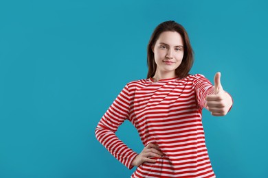 Woman showing thumbs up on light blue background, space for text. Like gesture