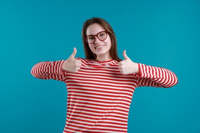 Photo of Happy woman showing thumbs up on light blue background. Like gesture